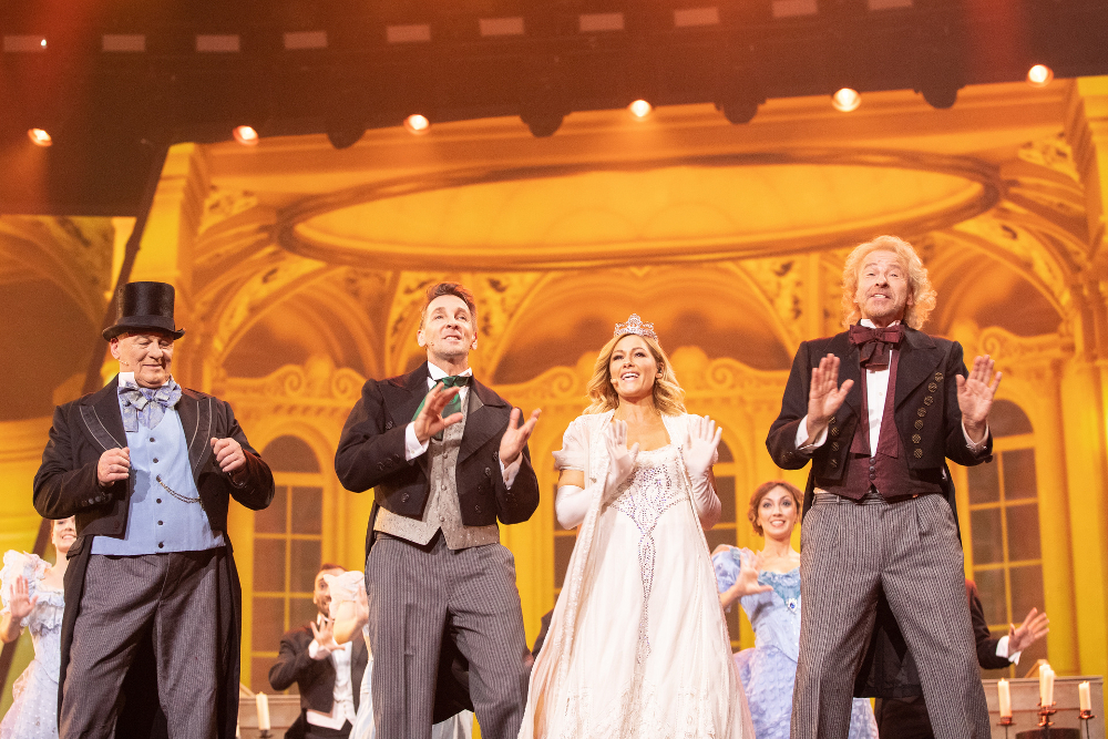 Heinz Hoenig, Mark Keller, Helene Fischer und Thomas Gottschalk stehen gemeinsam auf der Bühne, singen und tanzen zu Musik aus dem Musical Musical “My Fair Lady”.